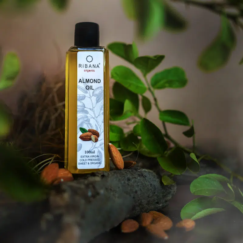 Ribana Organic Almond Oil 100ml in transparent bottle, golden oil, with white pump dispenser.